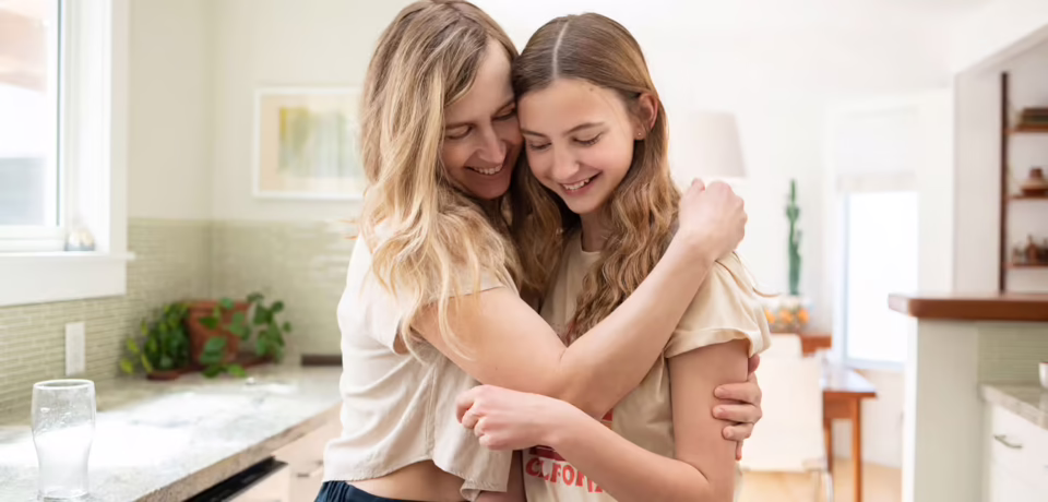 mom-hugging-her-teen-daughter-in-the-kitchen-navigating-the-teenage-years